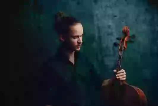 Der Cellist Johann von Ruthendorf hält sein Cello in der Hand.